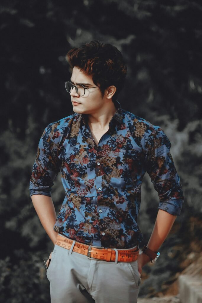 Confident man in floral shirt poses outdoors, exuding fashion-forward style.