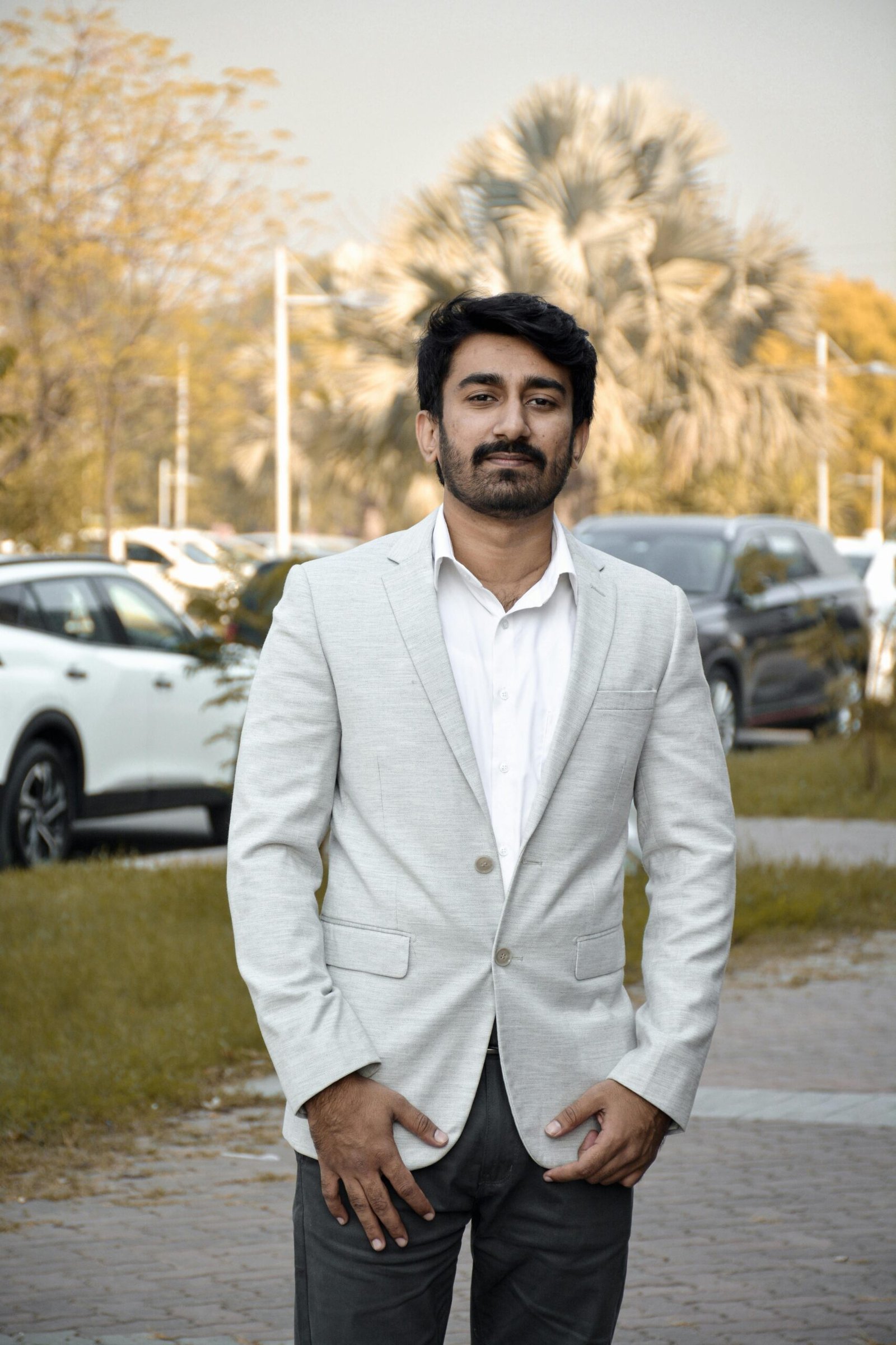 Elegant man in a white suit standing outdoors at a park in Islamabad, Pakistan.