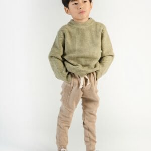 Confident ethnic child in trendy wear and sneakers standing with hands in pockets while looking away